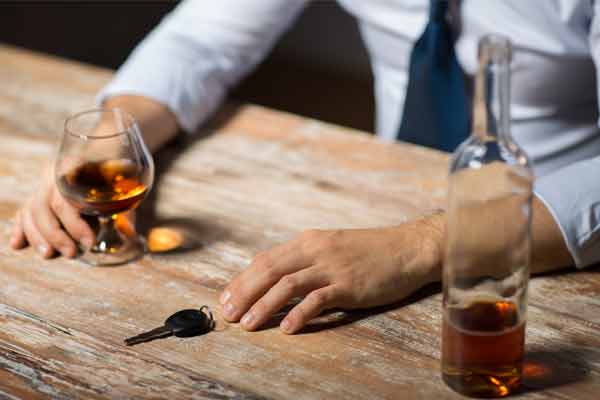 A man drinking at a bar with his car keys next to him.